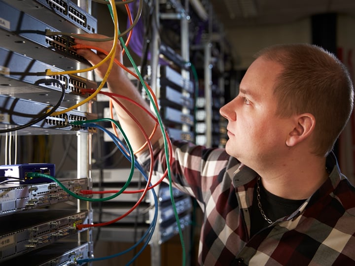 A researcher working with network equipment in the university lab